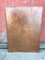 Front view of rectangular copper plate against weathered wooden background.
