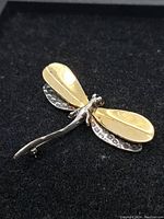 Dragonfly brooch showing front and two-tone design with textured silver wings and gold-tone layered top wings.
