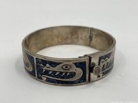 Front view of the sterling silver bracelet showing the blue inlaid animal head design with teeth and eye detail.