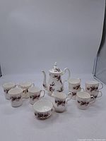 Full set view with coffee pot, six cups, creamer, and sugar bowl arranged on white background.