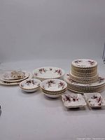 Full set of Royal Albert Lavender Rose dinnerware including multiple plates, bowls, and serving dishes arranged on a surface.