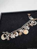 Full view of the sterling silver charm bracelet with all charms visible on a black background.