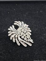Front view of Trafari rhinestone brooch showing clear rhinestones in a floral swirl silver-tone metal design.