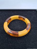 Full view of the circular Bakelite bracelet showing alternating solid yellow and amber translucent segments.