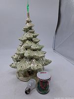 Vintage ceramic Christmas tree next to clear replacement light bulb and jar of colored bulbs.