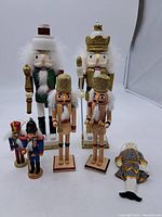 Full lot of seven vintage holiday nutcracker figures displayed on white surface.