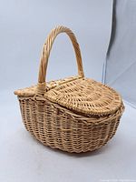 Wicker basket closed showing the woven texture, rounded shape with lid and handle.
