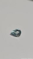 Photo of pear cut natural aquamarine gemstone showing light blue color and faceting details
