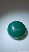 Close-up photo of vivid green natural onyx gemstone, polished round cabochon shape reflecting light spot.