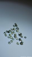 Clear photos showing multiple small calibrated oval alexandrite gemstones exhibiting green to yellow color change.