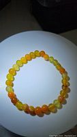 Yellow agate bead bracelet arranged in a circular fashion showing color and pattern variation of beads under focused lighting.