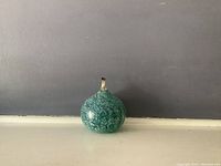 Photo showing the round green speckled artisan glass oil lamp with brass wick holder.