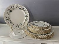 Full view of the stacked set of plates with one plate displayed on a stand showing floral pattern and gold rim
