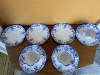 Top view of six Shelley fine bone china saucers arranged on a wooden surface showing the blue floral pattern.