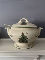 Front-facing photo of white ceramic turreen with lid and ladle, decorated with Spode Christmas Tree pattern including Christmas tree and holly