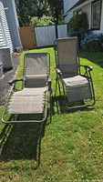 Two anti-gravity chairs positioned outdoors on grass, one fully reclined and the other upright