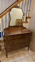 Front view of the antique dresser showing three drawers and large scalloped mirror.