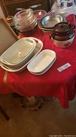 Photo of the assortment including white ceramic baking dishes, brown ceramic baked bean pot, metal pie pans, and glass lids.