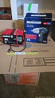 Photo of Powerfirst battery charger and Mastercraft impact wrench box side by side on stacked boxes.