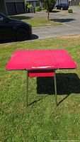 Red cracked ice laminated kitchen table with three segments and chrome trim legs shown open in outdoor light.