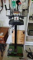 Front view of Craftsman electric grinder mounted on stand in garage environment, showing entire unit including grinding wheels, lamp and on/off switch.