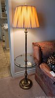 Full view of vintage floor lamp with glass table illuminated, next to a couch, showing lamp and shade details.