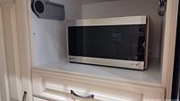 Front view of LG LMC0975ST stainless steel microwave oven on white shelf.
