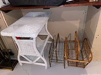 Side view of white wicker table with metal and bamboo magazine racks next to it on floor.