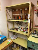 Full view of beige metal shelving unit holding various hand tools on pegboard and shelves.