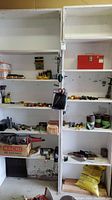 Wide view showing shelves containing various hand tools, a red toolbox, sanding rolls, and a corded power grinder.