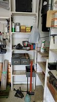 Photo shows shelving with assorted hand tools, a sledge hammer with red handle, clamps, and small containers with hardware.