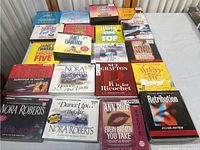 Multiple audiobook CDs on table showing various titles by Janet Evanovich, Nora Roberts, Sue Grafton, Ann Rule, and others all factory sealed