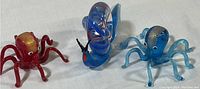 Photo of the three Murano glass miniatures: one snail with blue and white swirls and two octopus, one red with gold accents and one blue with silver accents.