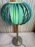 Side view of the vintage table lamp showing teal wooden curved slats of the outer shade and metal base with cord.