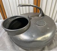Top and side view of the metal milking container opening showing the smooth metal surface and wide neck.