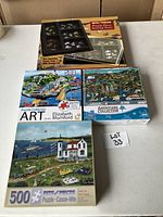 Photo showing the three 500-piece puzzles arranged neatly with the two-stackable puzzle sorter tray with storage lid placed above the puzzles.