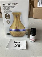 Photo showing the BetterLiving Aromatherapy Diffuser box and Esencia fragrance oil bottle on a table with a lot tag.