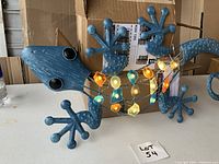 Side view of blue lizard wall hanging with multicolored lights, showing large eyes and detailed texture.