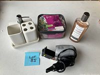 All items together on a tabletop, including blow dryer, curlers, bottle, and ceramic set with dispenser and holders