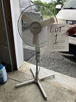 Full view of Honeywell pedestal fan showing adjustable height pole, base, and attached remote control with four buttons and LED indicators.
