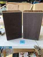 Pair of Pioneer speakers standing side by side on a white table, wooden frame with brown fabric grills
