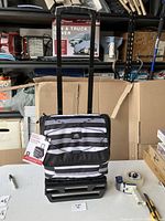 Full view of the rolling cooler bag with handle extended, black and white horizontal stripes.