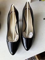 Top view of one pair of black pointed-toe women's high heels, showing pair side by side with tissue inside, appears brand new.