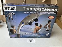 Box front showing the HoMedics TherapistSelect Wrap-Around Percussion Massager with heat feature, advertising adjustable handles and areas of use such as neck, shoulders, back, and lower back.
