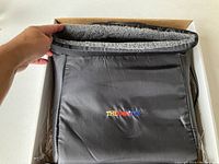 Close-up of the black foot therapy machine with gray inner lining, showing the Thermotex logo embroidered in color.