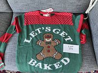 Full front view of the green and red knit sweater with gingerbread man and 'LET'S GET BAKED' text.