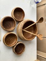 Set of one large wooden salad bowl, four smaller bowls, and two wooden mixing spoons.