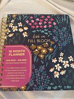 Front cover of the planner titled 'Live in Full Bloom' with floral artwork and key features of the planner date range and layout.