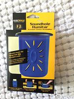 Front view of packaging showing the blue Soundhole Humitar humidifier and key features such as sponge holding capacity and moisture release mechanism.