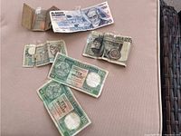 Collection of six foreign bank notes laid out on a surface: two Hong Kong ten dollar notes, Mexican peso, Italian lira, and others.